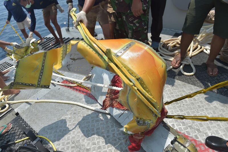 Members of the Indonesian Navy place parts of the ill-fated Lion Air flight JT 610 onto the deck of their ship during search operations at sea. AFP