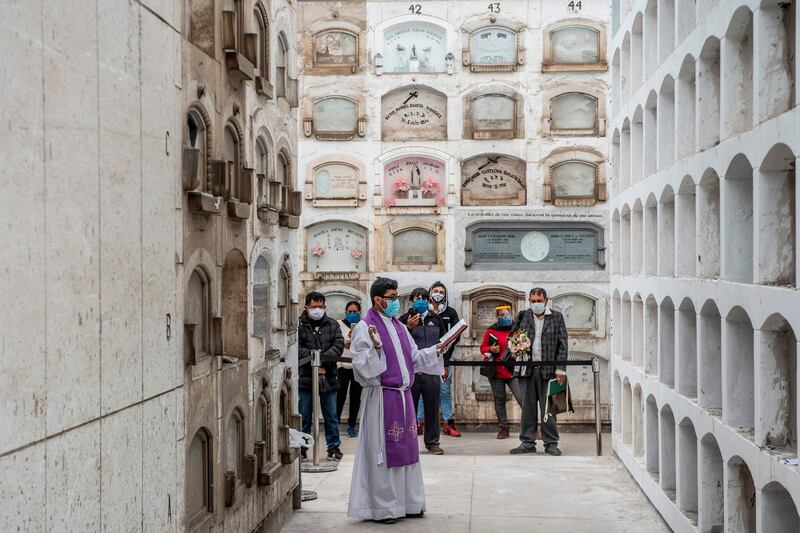 A priest conducts a ceremony after the funeral of COVID-19 victims at El Angel cemetery, in Lima. AFP