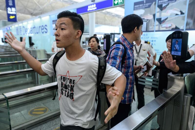 Two travellers react after protesters tried to block them from entering the departures gates area during another demonstration at Hong Kong's international airport on August 13, 2019.  AFP