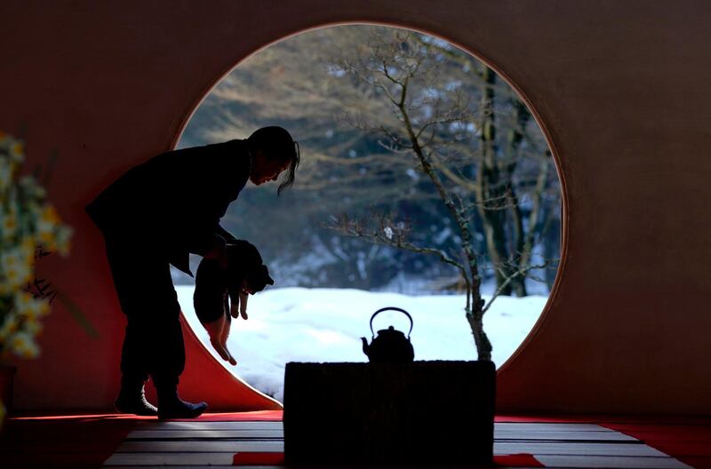 A temple staff lifts a pet cat as a snow-covered garden is seen through a window of Meigetsuin Zen temple in Kamakura, west of Tokyo. Shizuo Kambayashi / AP Photo