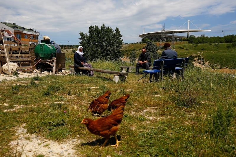 Local residents sit at an area, near to Ataturk Olympic Stadium, background, in Istanbul. AP Photo