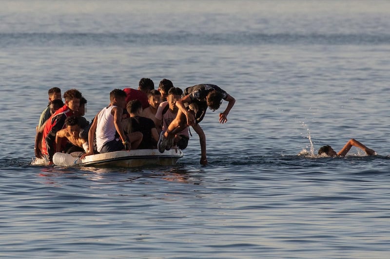 A young man jumps from a small boat packed with migrants that left Morocco to try to reach Ceuta. EPA