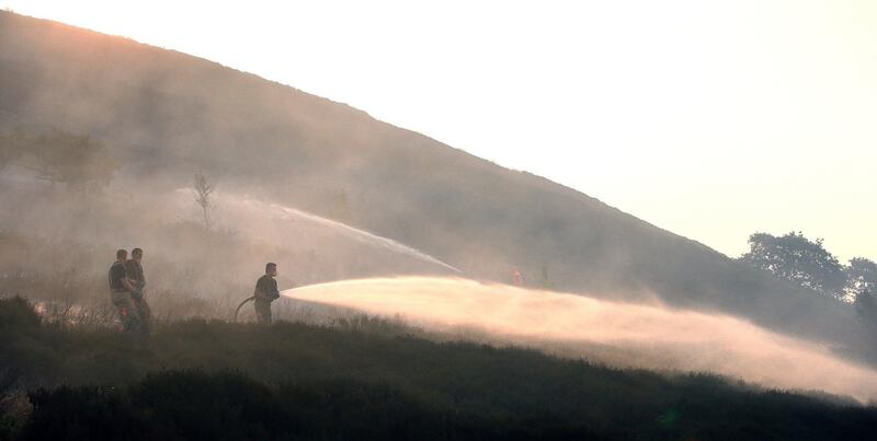 Firefighters damp-down the scorched land as they tackle a wildfire on Saddleworth Moor, England, which continues to spread and police have declared the blaze as a major incident, Wednesday June 27, 2018. The fire started on Sunday then reignited Monday amid Britain's heatwave and has devastated land around the village of Carrbrook, forcing the evacuation of nearby homes. (Peter Byrne/PA via AP)