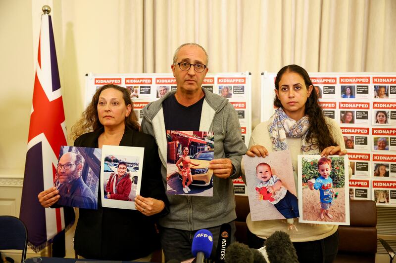 Ayelet Svatitzky, David Barr and Ofri Bibas Levy show pictures of their loved ones who were taken hostage by Hamas. Reuters