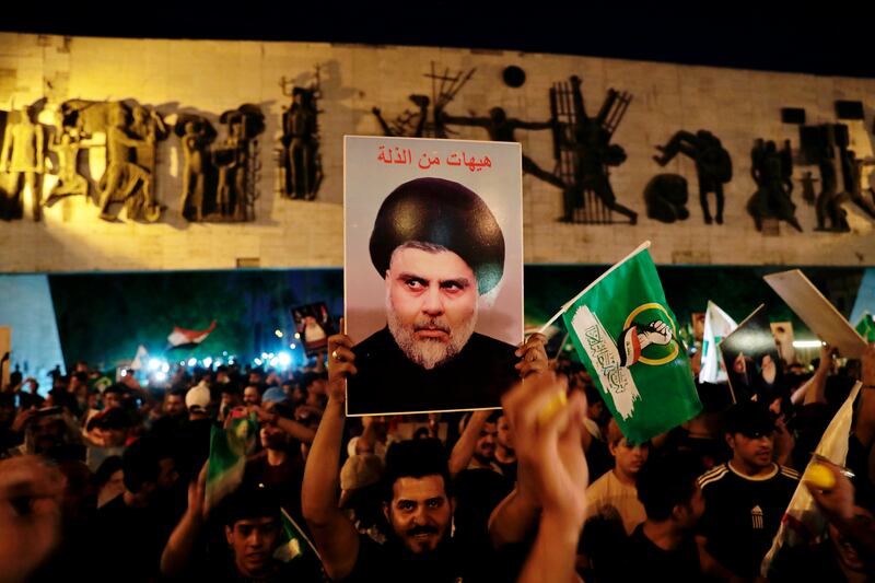 Followers of Shiite cleric Muqtada al-Sadr celebrate holding his poster, after the announcement of the results of the parliamentary elections in Tahrir Square, Baghdad, Iraq, on Monday, October 11, 2021. AP