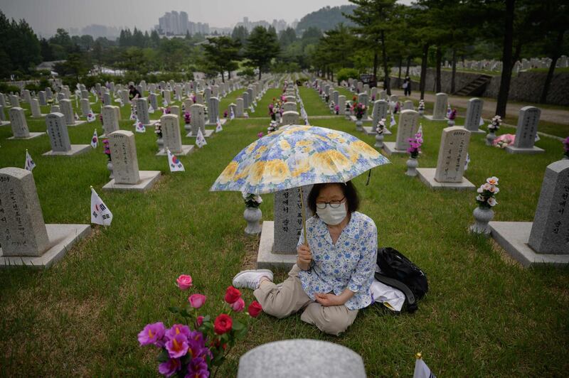 Kim Myung-sook sits before a grave of her brother at the National Cemetery as South Korea marks Memorial Day in Seoul. AFP
