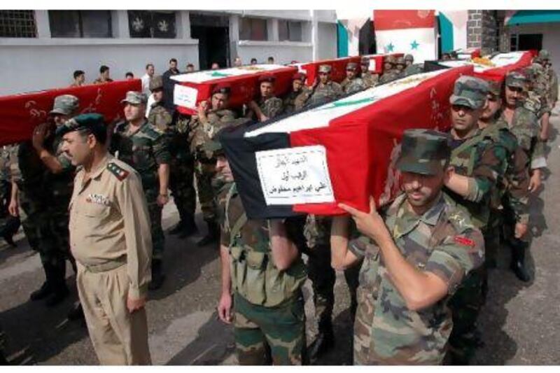 Syrian soldiers carry the coffins of comrades killed in recent violence, during their funeral procession at the military hospital in Homs. AP Photo / SANA