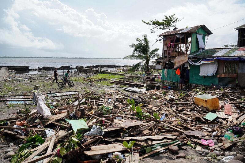 Residents walk past a house damaged during Typhoon Phanfone in Tacloban, Leyte province in the central Philippines. AFP