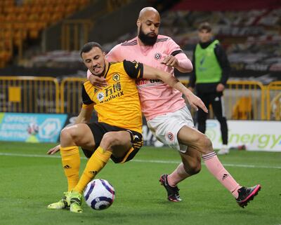 WOLVERHAMPTON, ENGLAND - APRIL 17: Romain Saiss of Wolverhampton Wanderers and David McGoldrick of Sheffield United compete for the ball during the Premier League match between Wolverhampton Wanderers and Sheffield United at Molineux on April 17, 2021 in Wolverhampton, England. Sporting stadiums around the UK remain under strict restrictions due to the Coronavirus Pandemic as Government social distancing laws prohibit fans inside venues resulting in games being played behind closed doors. (Photo by Geoff Caddick - Pool/Getty Images)