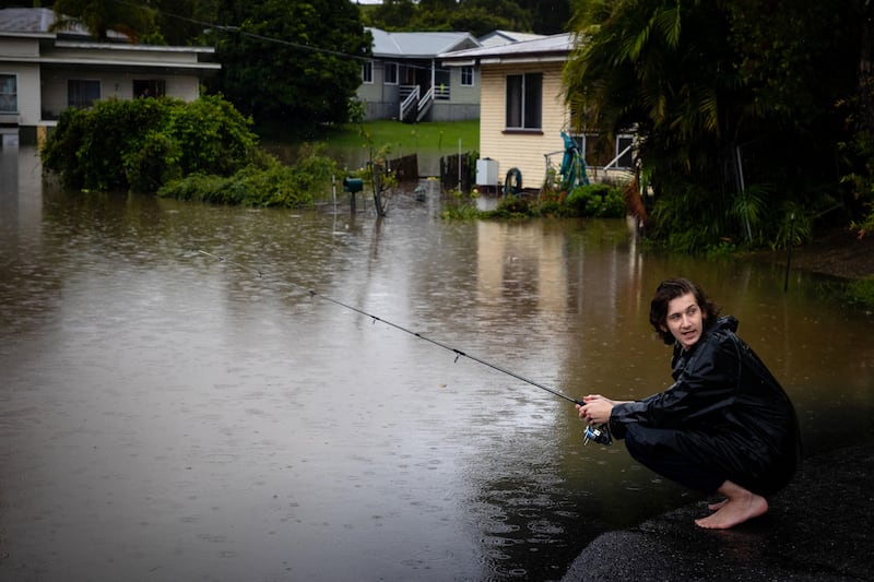 Resident Jai Connors fishes in rising floodwater from the swollen Bremer river in front of his home in the city of Ipswich. AFP
