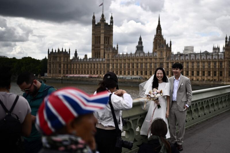 A newly married couple pose next to people waiting in line. AFP
