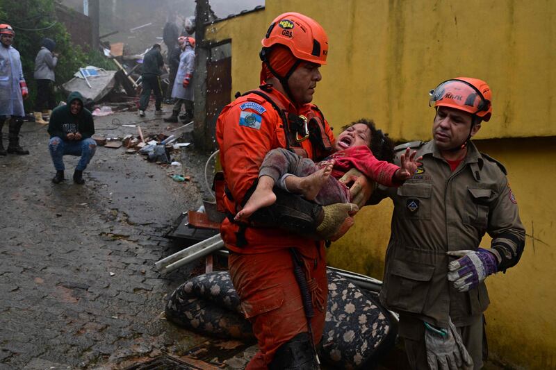 Members of the Civil Defence rescue a girl after her family home was destroyed by heavy rains in Petropolis, Brazil. AFP