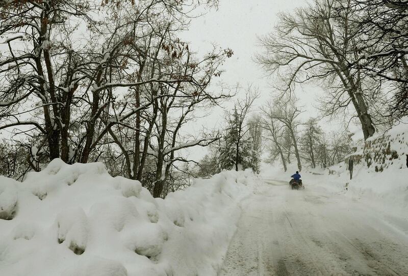 Youths drive their quad bikes on a snow-covered road near the town of Bcharre in Mount Lebanon. AFP