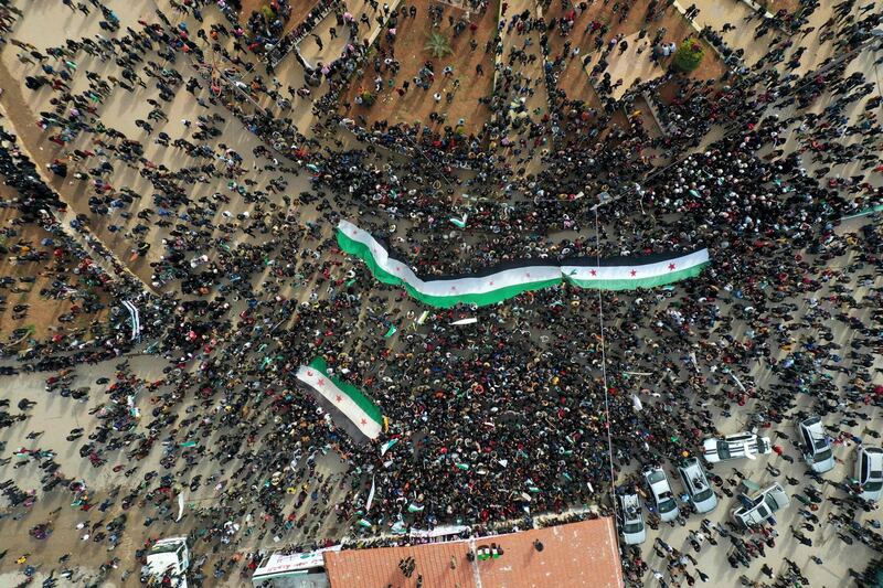 An aerial picture shows Syrians waving the national flag during a gathering in the rebel-held city of Idlib. AFP