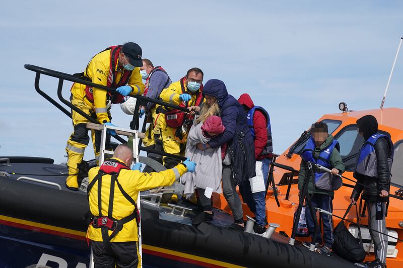 Members of the Royal National Lifeboart Institution (RNLI) assist migrants after they were brought into Dungeness, Kent. The UK Home Office has said there are 70 unaccompanied child migrants staying in hotels. Photo: PA