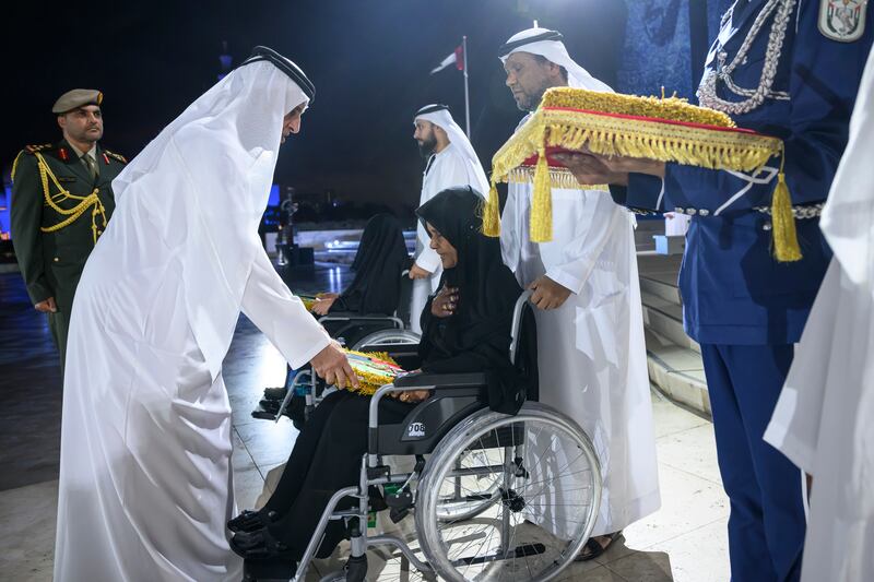 Sheikh Saud, UAE Supreme Council Member and Ruler of Ras Al Khaimah, left, presents a medal to a family member of a martyr.