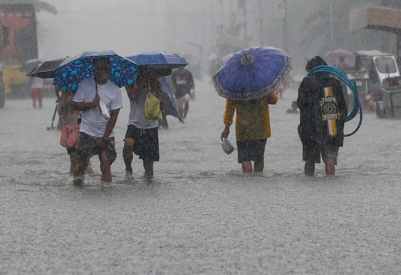 Filipinos walk through floodwaters in Malabon City, north of Manila. Rolex De La Pena / EPA