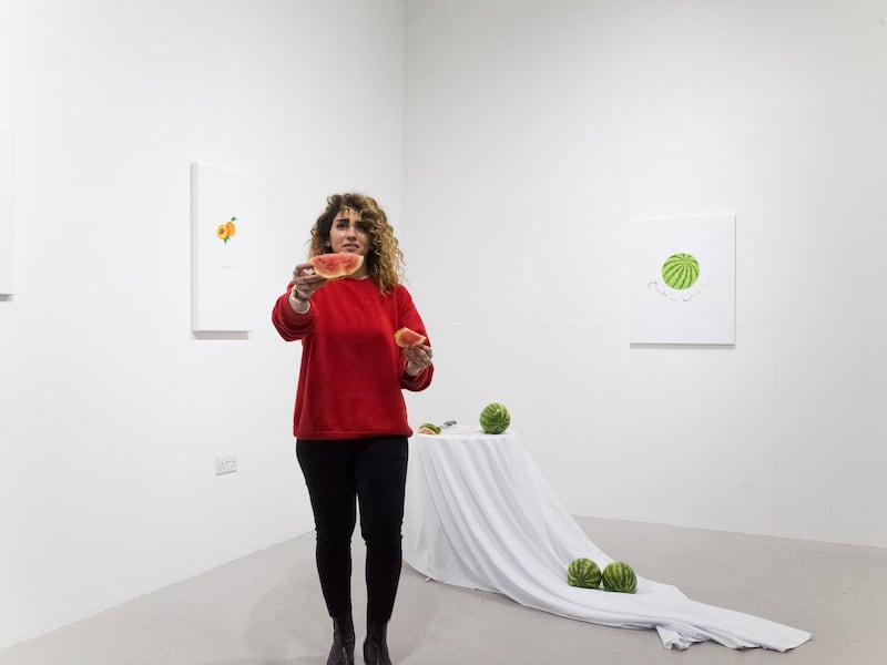 Areej Kaoud hands out pieces of cut watermelon in her opening performance. Courtesy of the artist and Indigo+Madder