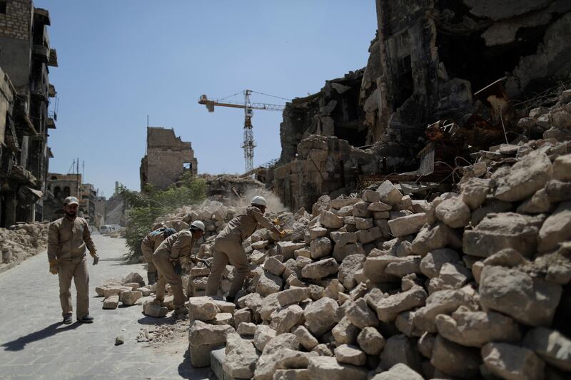 In photo shows Syrian workers remove rubble from damaged shops in the old city of Aleppo, Syria. AP