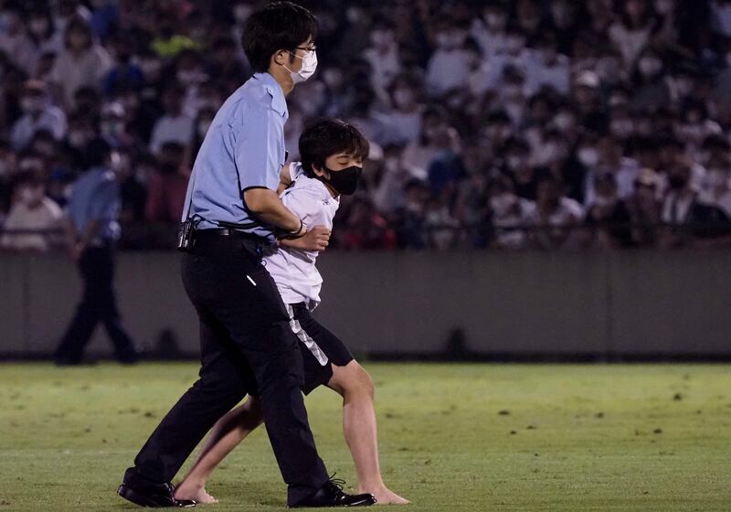 A security officer holds a fan who invaded the pitch during PSG's training session in Tokyo. AFP