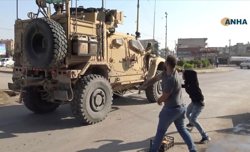 In this frame grab from video provided by Hawar News, ANHA, the Kurdish news agency, residents who are angry over the U.S. withdrawal from Syria hurl potatoes at American military vehicles in the town of Qamishli, northern Syria. AP