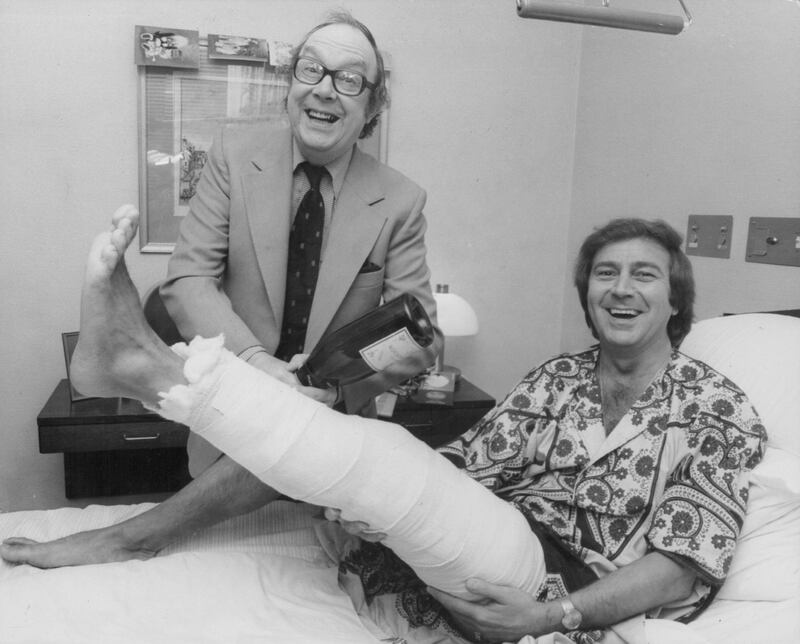 Singer and entertainer Des O'Connor in hospital with a broken leg, being visited by friend and fellow entertainer Eric Morecambe, Wellington Hospital, London, February 27th 1978. (Photo by Frank Barratt/Keystone/Getty Images)