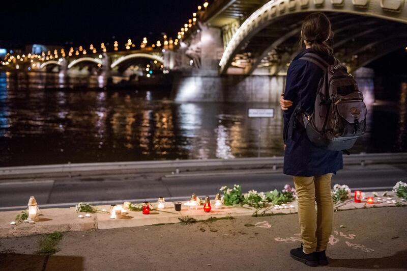 epa07613502 A woman stands by flowers and candles placed on the riverbank to pay tribute to the victims of the capsized boat at Margaret Bridge, in Budapest, Hungary, 30 May 2019. A sightseeing boat carrying 33 South Korean tourists collided with a large river cruise ship on River Danube near the bridge a day earlier, killing at least seven tourists. Seven tourists have been rescued with rescue efforts ongoing for the missing 21 people.  EPA/Zoltan Balogh HUNGARY OUT
