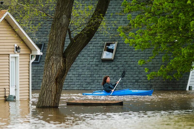 People use kayaks to assess the damage at homes in their neighbourhood on Oakridge Road on Wixom Lake. Midland Daily News via AP