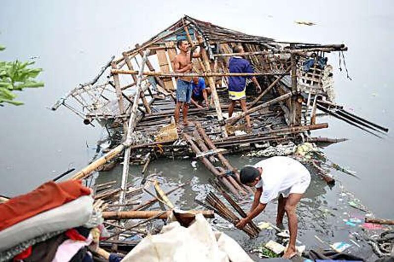 Residents try to salvage their damaged shanty yesterday along the coastal road in Paranaque in suburban Manila.
