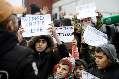 Migrants hold signs as they protest against repatriation outside the transport and logistics centre in the Grodno region. Reuters