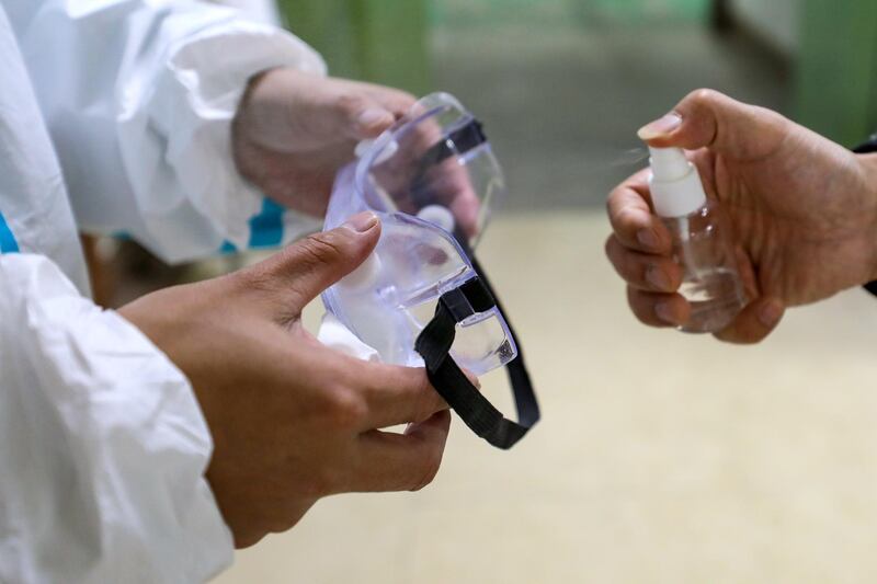 The ambulance staff sprays alcohol on their goggles after a transfer mission in Wuhan, Hubei province, China.  EPA