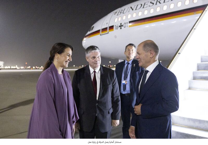 Mariam Al Mheiri, UAE Minister of Climate Change and the Environment, and Alexander Schoenfelder, German ambassador to the UAE, welcome German Chancellor Olaf Scholz, right, at the Abu Dhabi Presidential Airport. Ryan Carter / UAE Presidential Court