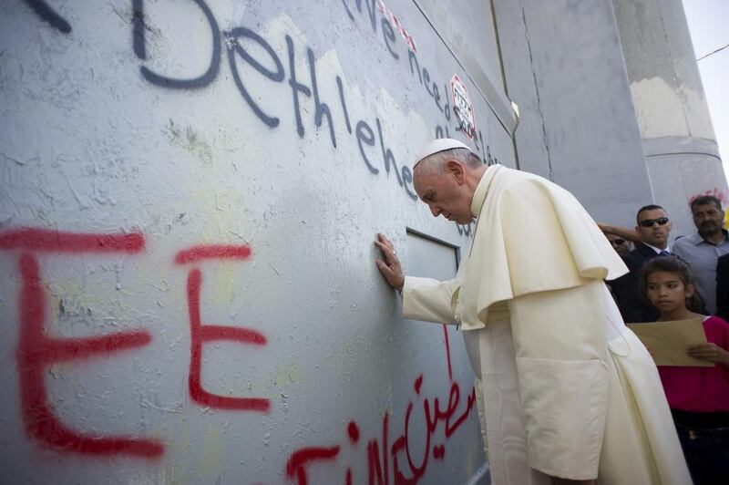 A handout picture released by the Vatican press office shows Pope Francis praying at Israel’s separation barrier on May 25, 2014 after he made an unscheduled stop at the security wall drawing attention to the towering eight-metre high concrete wall topped by a guard tower. Vatican press office/AFP Photo