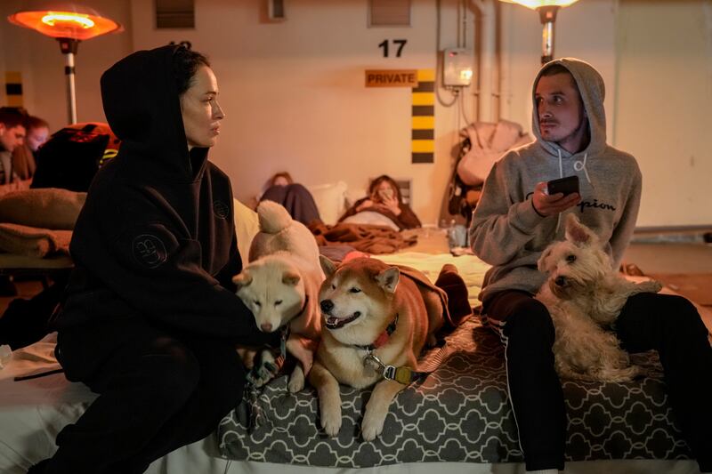 A couple and their dogs sit in a hotel underground car park, which has been turned into a bomb shelter in Kiev, Ukraine. AP