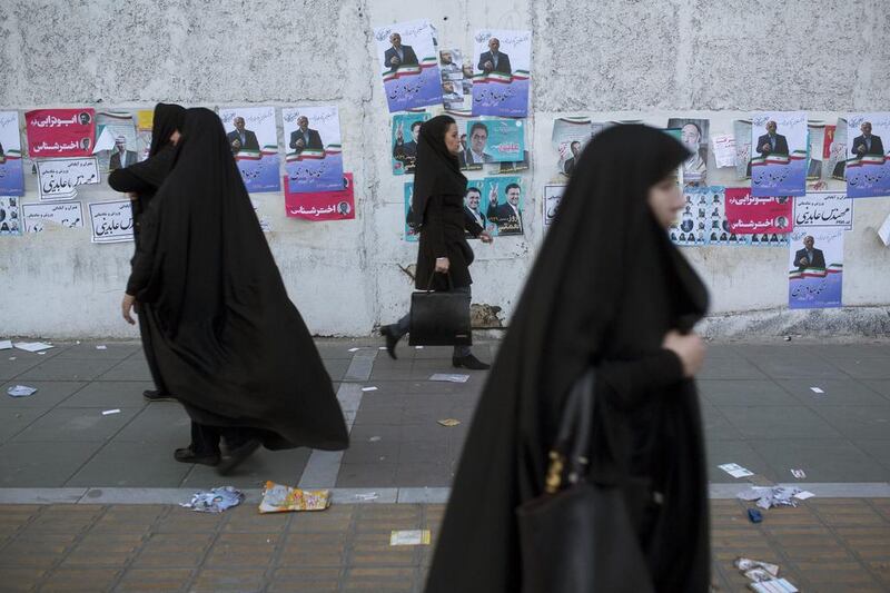People walk past electoral posters in downtown Tehran (Photo by Majid Saeedi/Getty Images)