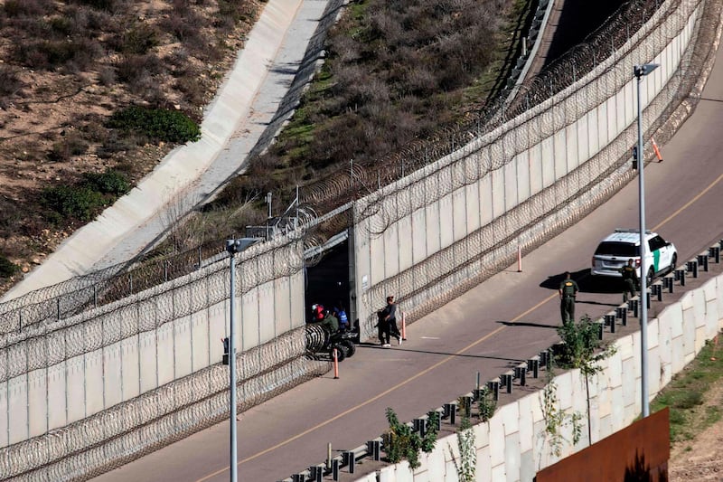 A group of Central American migrants -travelling in a caravan- is taken in to custody by US Border Patrol after crossing the Mexico-US border fence to San Diego County, from Tijuana, Baja California state, Mexico on December 16, 2018.  Thousands of Central American migrants, mostly Hondurans, have trekked in a caravan for over a month in the hopes of reaching the United States. / AFP / Guillermo Arias
