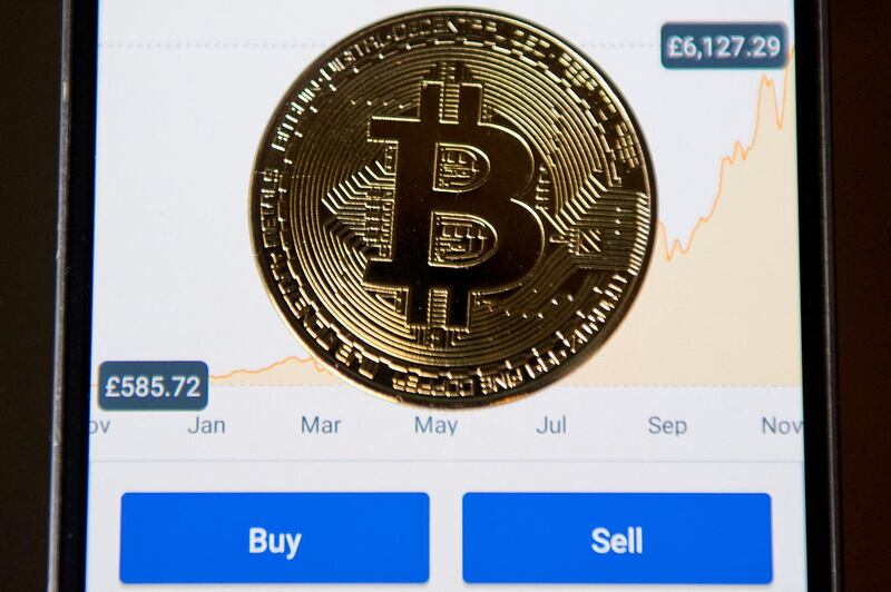 (FILES) In this file photo taken on November 21, 2017, a gold plated souvenir Bitcoin coin is arranged for a photograph on a smart phone on an app for the digital asset broker, Coinbase, in London. Coinbase, an exchange for bitcoin and other cryptocurrencies, filed papers on February 25, 2021, to become publicly traded in the latest sign of the rise of digital currencies. / AFP / Justin TALLIS

