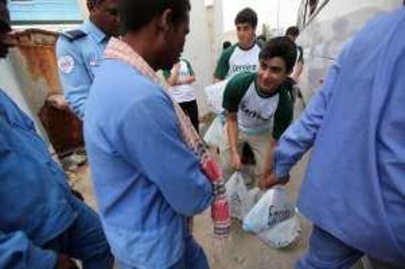 May 5, 2010/ Abu Dhabi /  Julien Sullivan, 15, a student at the American Community School helps hand out bags of food to labourers a block from the school May 5, 2010. Julien Sullivan organized about 30 volunteer students to help put together a 140 bags of food that that they handed out to workers as they finished up their day at work. (Sammy Dallal / The National)


