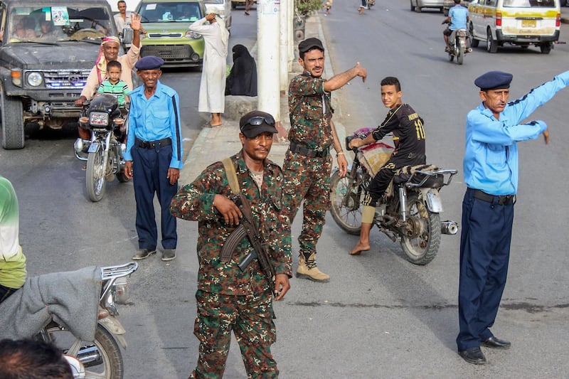 Yemeni policemen (in blue) and Huthi fighters control the traffic at the centre of the port city of Hodeidah, around 230 kilometres west of the capital Sanaa, on May 13, 2019. The United Nations said on May 12, 2019 that a Yemeni rebel withdrawal from key Red Sea ports was proceeding as planned, after the government accused the insurgents of faking the pullout. / AFP / STR
