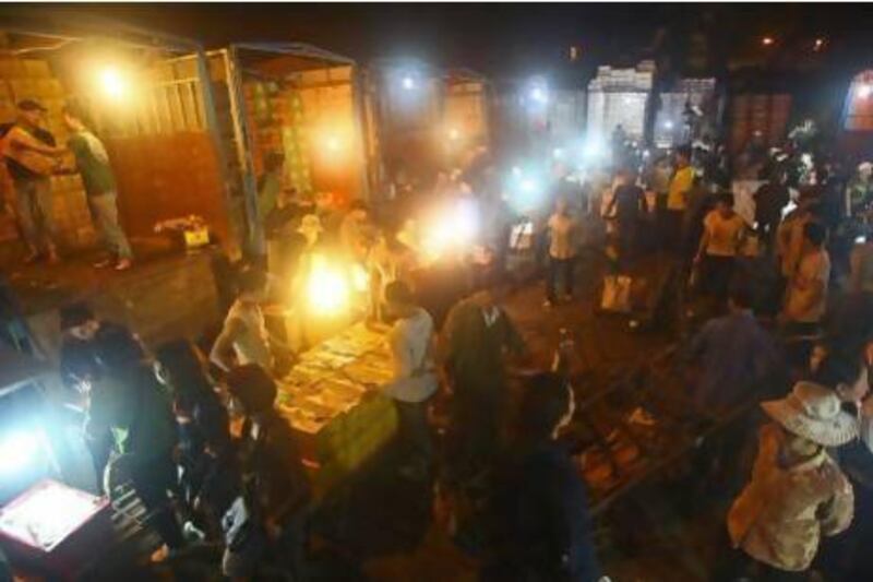 Porters unload boxes of Chinese fruits near traders at Long Bien wholesale market for fruits and vegetables in Hanoi.