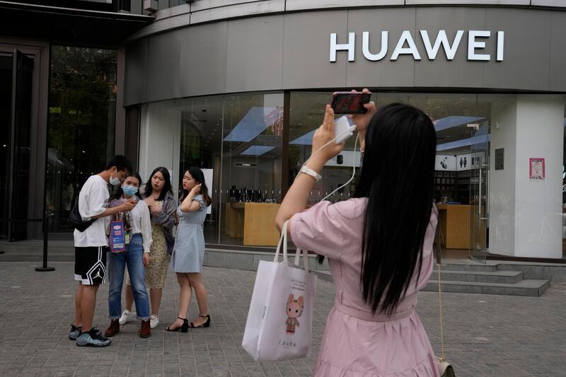 Shoppers stand outside a Huawei store in Beijing on Wednesday, June 2, 2021. Huawei is launching its own HarmonyOS mobile operating system on its handsets as it adapts to losing access to Google mobile services two years ago after the U.S. put the Chinese telecommunications company on a trade blacklist. (AP Photo/Ng Han Guan)