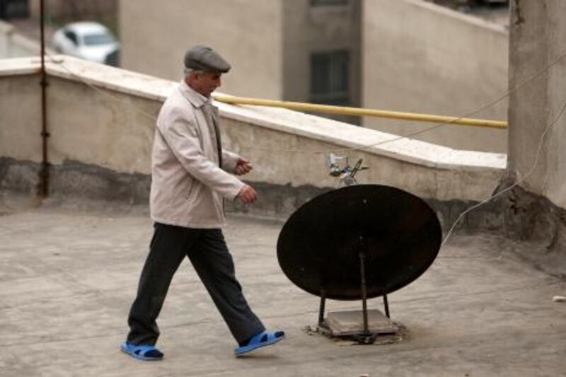 An Iranian man walks past a satellite dish on a rooftop in northern Tehran January 15, 2011. REUTERS/Morteza Nikoubazl (IRAN - Tags: BUSINESS)