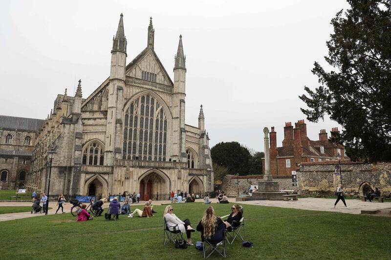 Members of the public sit outside Winchester Cathedral in Winchester. AFP