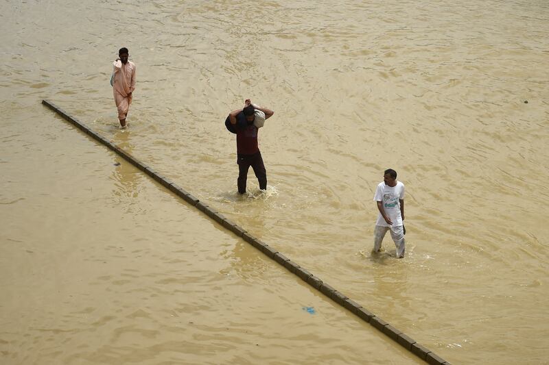 Commuters wade through a flooded street after heavy rain. The monsoon rains continue to lash Pakistan, triggering flash floods in some parts of the country. AFP