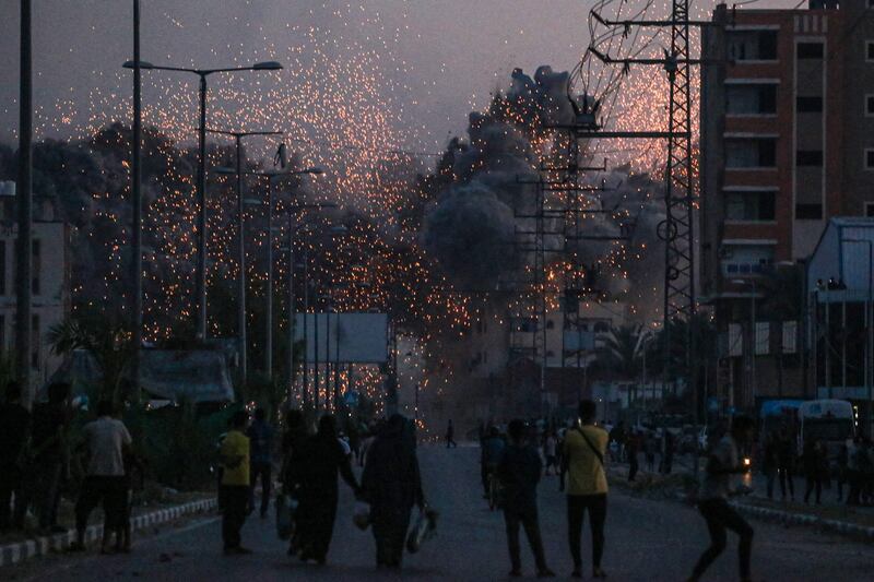 Palestinians watch smoke billowing after an Israeli air strike on Deir Al Balah in the central Gaza Strip. AFP