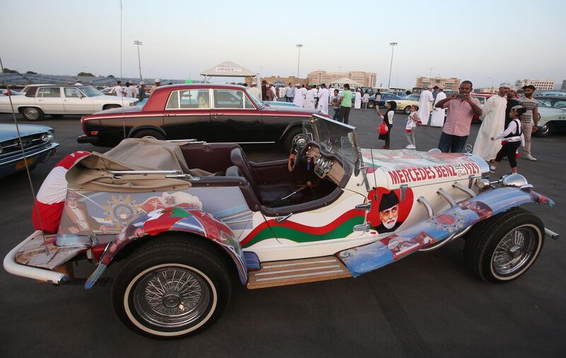A Omani takes a picture of Mercedes Benz model 1929 vintage auto, with decals bearing the image of the country's leader Sultan Qaboos bin Said, during an annual classic car show in the capital Muscat on November 17, 2017. / AFP PHOTO / MOHAMMED MAHJOUB