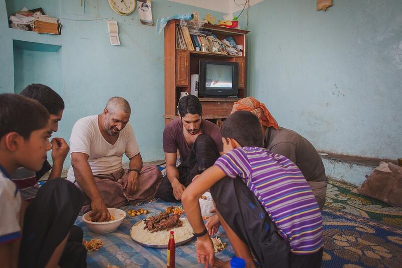 Zaher Sulaiman and his family enjoy shuwah, an Eid delicacy of meat wrapped in banana leaves and baked underground for days. Ania James for The National