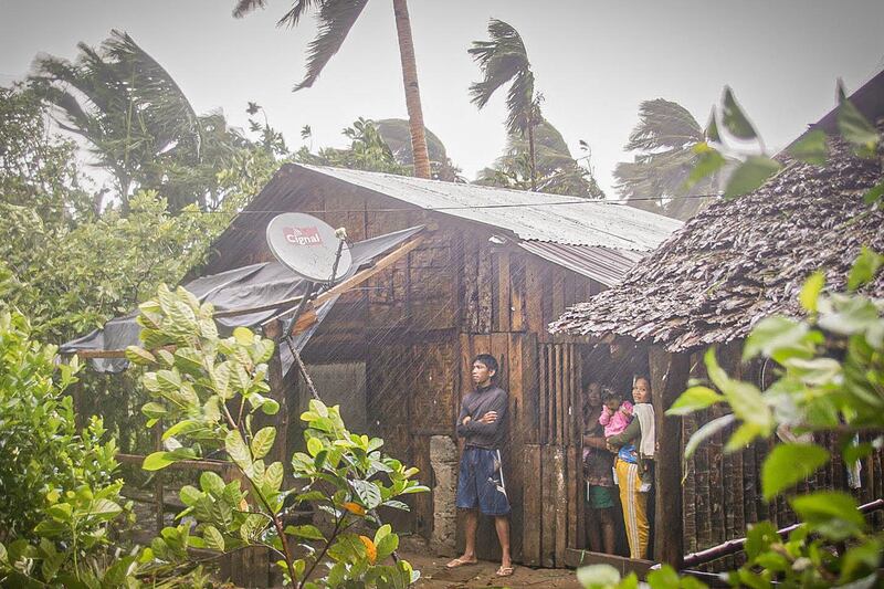 Residents take shelter by their house as they observe rain and wind in Can-avid town, Eastern Samar province, central Philippines, as Typhoon Vongfong makes landfall. AFP