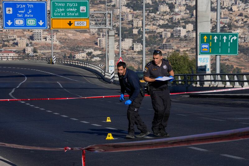 Israeli forensic police officers inspect the scene of an explosion at a bus stop in Jerusalem. AP