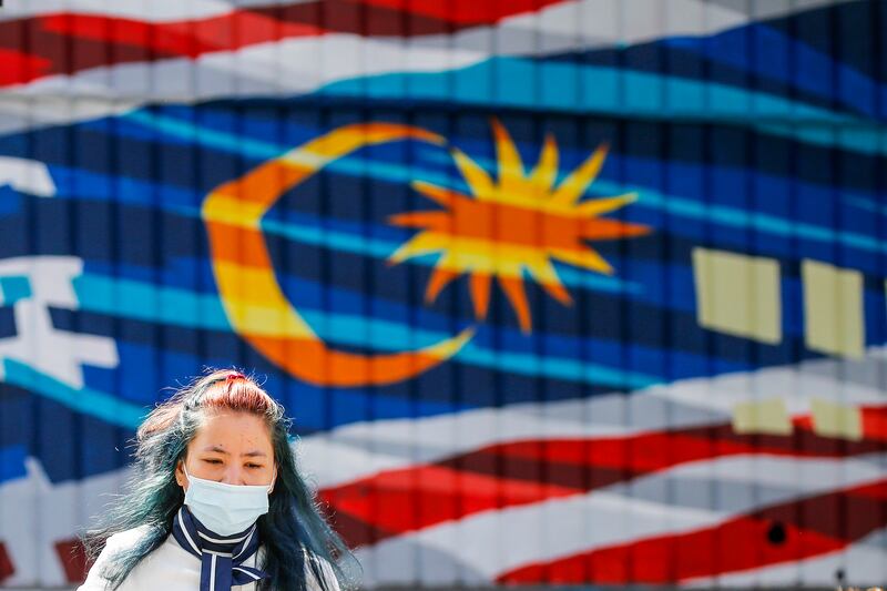 A woman wearing a face mask walks in front of a mural depicting the Malaysian flag, in Kuala Lumpur, Malaysia. Photo: EPA